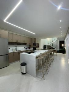 a kitchen with a white counter and bar stools at Maison Joia dos Vinhedos in Vinhedo