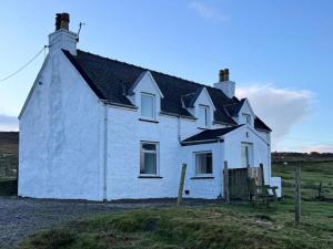 a white house with a black roof on a field at 2 Borrodale - Sleeps 4 & Beautiful Mountain View in Glendale