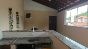 a kitchen with a counter with a sink and a window at Alugo kitnet com café da manhã in Aparecida