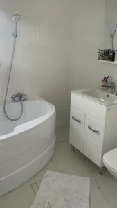 a white bathroom with a tub and a sink at Apartament in Suceava