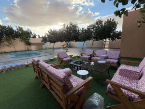a patio with chairs and tables and a pool at أكواخ كيفاء الريفية in Tabuk