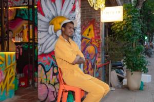 a man sitting on a orange chair in front of a building at Wow Tam Coc Homestay in Vũ Lâm