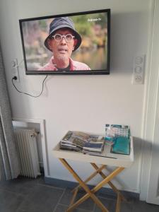 een flatscreen-tv aan een muur met een tafel bij Les oyats in Le Crotoy
