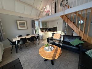a living room with a black couch and a table at Huisje 118 bungalowpark Simpelveld in Simpelveld