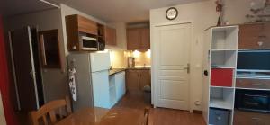 een keuken met een witte koelkast en een klok aan de muur bij Appartement résidence des Bottières in Saint-Pancrace