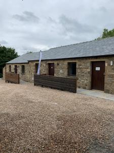 ein Steingebäude mit zwei Bänken davor in der Unterkunft 3 Peaks Bunkroom in Settle