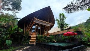 a small hut with a red umbrella in a garden at Wana Bamboo House by ecobreeze in Sidemen