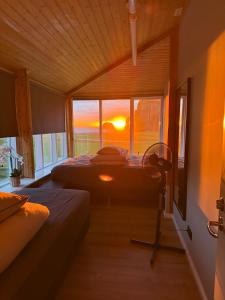 a bedroom with two beds and a window and a fan at Þórsheimili - Rooms in Vestmannaeyjar