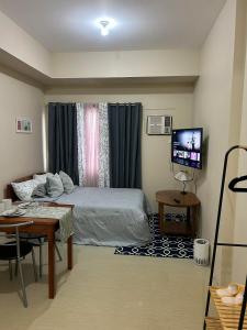 a bedroom with a bed and a table and a television at Avida Tower 1, Unit 2003 - Chi's Place in Cagayan de Oro
