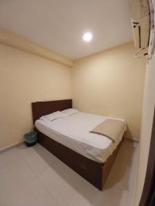 a small bedroom with a bed with white sheets at SHAMA HoTEL in Kuala Lumpur