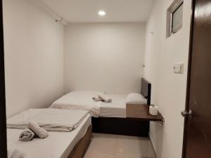 two beds in a small room with white walls at SHAMA HoTEL in Kuala Lumpur +9 photos