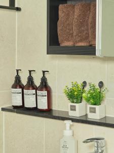 a shelf with three bottles of soap and plants on it at Soul House in Seoul +23 photos