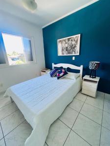 a bedroom with a large bed with a blue wall at Casa Verde Bertioga, um espaço cheio de charme com três praias - Indaiá, Pedra Selada e Riviera de São Lourenço para visitar a pé! in Bertioga +89 photos