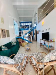 a living room with a couch and a staircase at Casa Verde Bertioga, um espaço cheio de charme com três praias - Indaiá, Pedra Selada e Riviera de São Lourenço para visitar a pé! in Bertioga