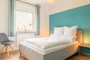 a bedroom with a white bed with a window and a chair at Hofgut Eveshausen - Dreiseitenhof - Spielscheune - Landidylle - Hofleben in Dommershausen