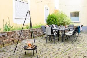 a patio with a table and chairs and a fire pit at Hofgut Eveshausen - Dreiseitenhof - Spielscheune - Landidylle - Hofleben in Dommershausen