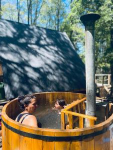 two women in a hot tub in a wooden tub at Cabañas bosque sur in Curarrehue