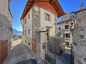 a stone building with a wooden roof on a street at BBkey La cjase SOT LA STRETE in Arta Terme