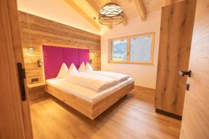 een slaapkamer met een groot bed met een paars hoofdeinde bij dein Dahoam Boutique Appartements in Gröbming