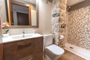 een badkamer met een wastafel, een toilet en een spiegel bij Encanto de Valderrobres in Valderrobres