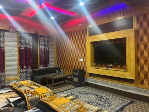a room with a tv and a couch and a table at Hotel Apex in Srinagar