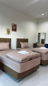 two beds sitting next to each other in a room at บุณยาเพลส เด่นชัย แพร่ in Den Chai