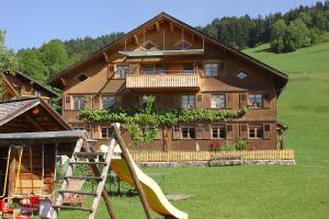 ein großes Holzhaus mit einer Rutsche davor in der Unterkunft Ferienbauernhof Schneider in Schwarzenberg im Bregenzerwald