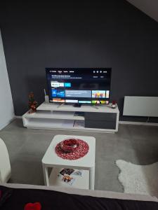 een woonkamer met een grote tv en een tafel bij Studio apartman Laura in Vinkovci