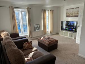 a living room with a couch and a tv at Chartsworth 4 Bedrooms Spacious House in Harold Wood