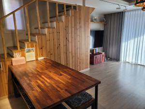 a living room with a wooden table and a staircase at Red Casa in Seogwipo