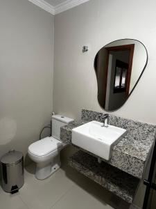 a bathroom with a toilet and a sink and a mirror at quarto standart 2 pousada village in Guarapari