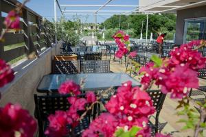 een patio met tafels en stoelen en roze bloemen bij Ivory Serenity in Theologos