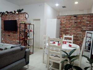 een woonkamer met een tafel en stoelen en een bakstenen muur bij Sava & Double Rooms in Prijedor