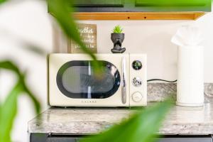 a microwave on a counter with a plant on top at Downtown Columbus & Short North 2BR Home - Sleeps up to 10 Guests - By Convention Center & Nationwide Arena - Free Parking - Over 5,800 Five Star Stays - Casita Verde by Jungle House in Columbus