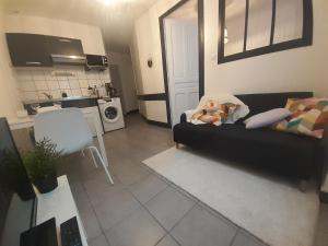 a living room with a black couch and a kitchen at Elise en plein coeur de la ville in Saint-Étienne
