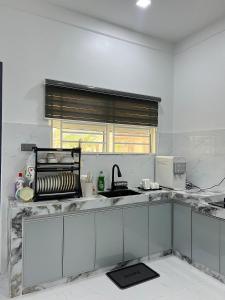 a white kitchen with a sink and a window at Alaisya Homestay in Kampung Raja