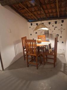 a dining room table with four chairs and a chandelier at Vila Borogodó- Casa in Barra Grande