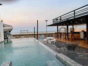 a swimming pool with chairs and tables and a boat at บ้านดาริน บีช Baan Darlin Beach in Phetchaburi