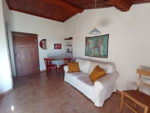 een woonkamer met een witte bank en een tafel bij Casa MarJù in Montemassi