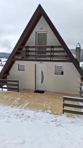een huis met een gambrel dak in de sneeuw bij Vikendica Luka in Han Pijesak