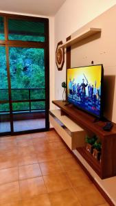 a living room with a flat screen tv at Exelente Localiazação - 50m Enseada e Pitangueiras - Apt Saint Patrick in Guarujá