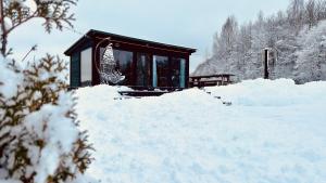 a small building covered in snow next to a pile of snow at Melnā kalna kamene, sauna iekļauta cenā in Vestiena