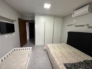 een slaapkamer met een bed, een kast en een tv bij Casa com piscina capão da canoa in Capão da Canoa