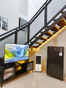 a living room with a tv and a staircase at Villa Dino Park Batu in Karangploso