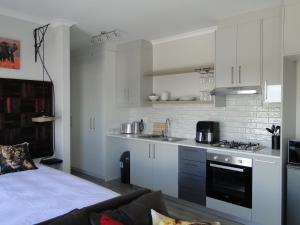 a kitchen with white cabinets and a stove top oven at Fresh Air in Cape Town