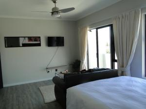 a bedroom with a bed and a couch and a window at Fresh Air in Cape Town