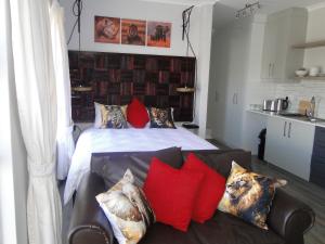 a bedroom with a bed with red pillows and a couch at Fresh Air in Cape Town
