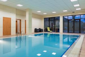 a large swimming pool with blue water in a building at Holiday Studio in Kozin