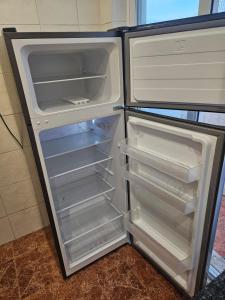 an empty refrigerator with its door open in a kitchen at spacious guest rooms in Lisbon