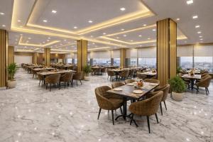 a dining room with tables and chairs and windows at Hotel The Prithvi Near Delhi Airport in New Delhi